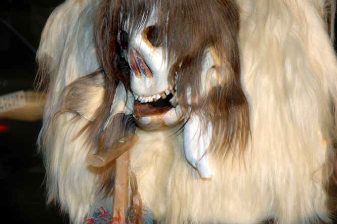 An der Lötschentaler Fasnacht grinst ein behaarter Totenschädel auf dem buckligen Fellkörper. Die Maske ist aus Holz geschnitzt.